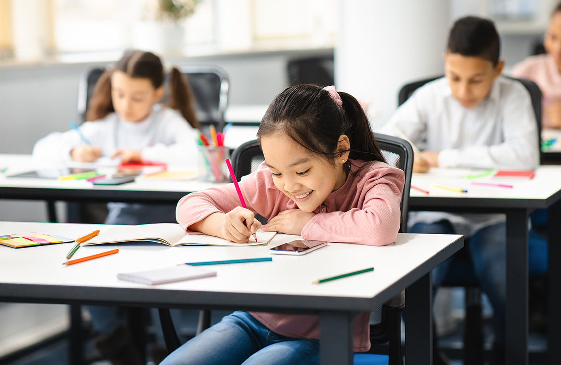 Primary school student studying attentively at her desk during a lesson in a primary school tuition centre classroom