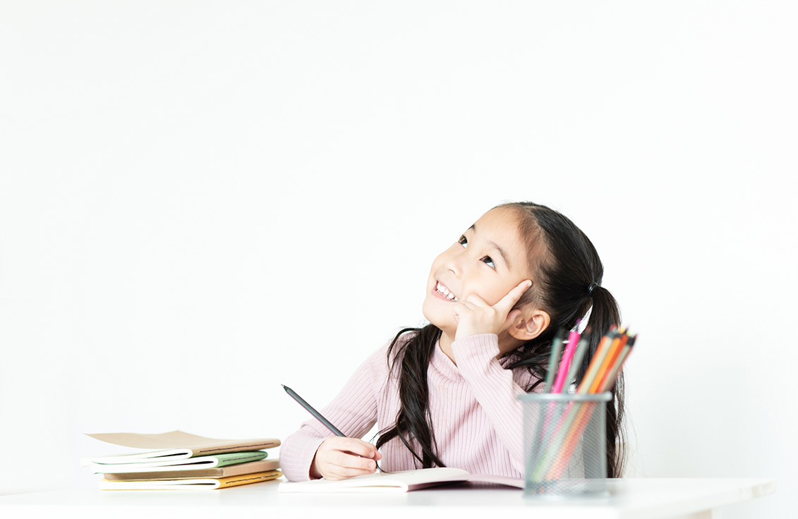 Upper primary school student sitting at her desk in a tuition classroom, studying with a thoughtful expression while preparing for PSLE